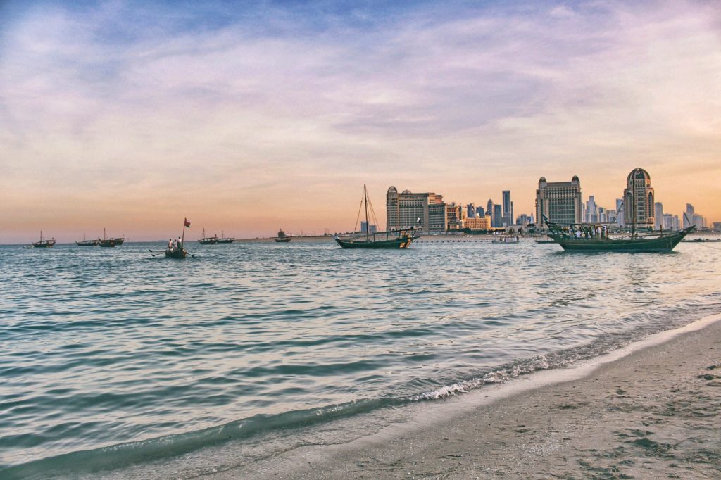 Sunset time at Doha Skyline. Traditional dhow. Ocean. Orange sky. Golden hour