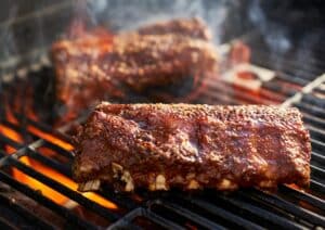 bbq ribs grilling over flaming grill